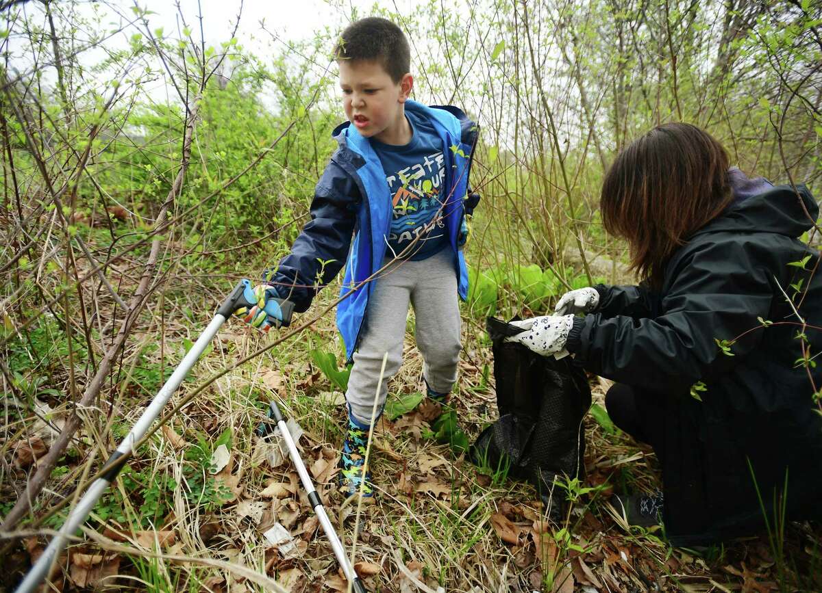 Jeremiah, 7, and his mom Vicky Siemieniewicz, of Oxford, gather trash from the banks of Bunnell's Pond as part of an Earth Day clean up at Beardsley Park in Bridgeport, Conn. on Saturday, April 22, 2023.