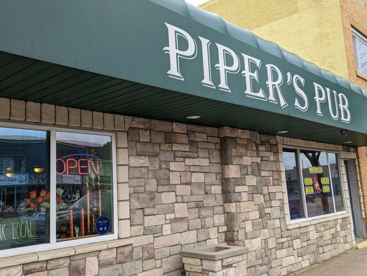 Tower of onion rings dripping with barbecue sauce on top of a burger