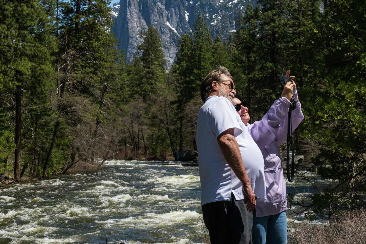 Dan and Teresa Hoffman, a Burbank couple who have visited Yosemite National Park several times, take selfies Thursday along the Merced River as it nears flood stage.