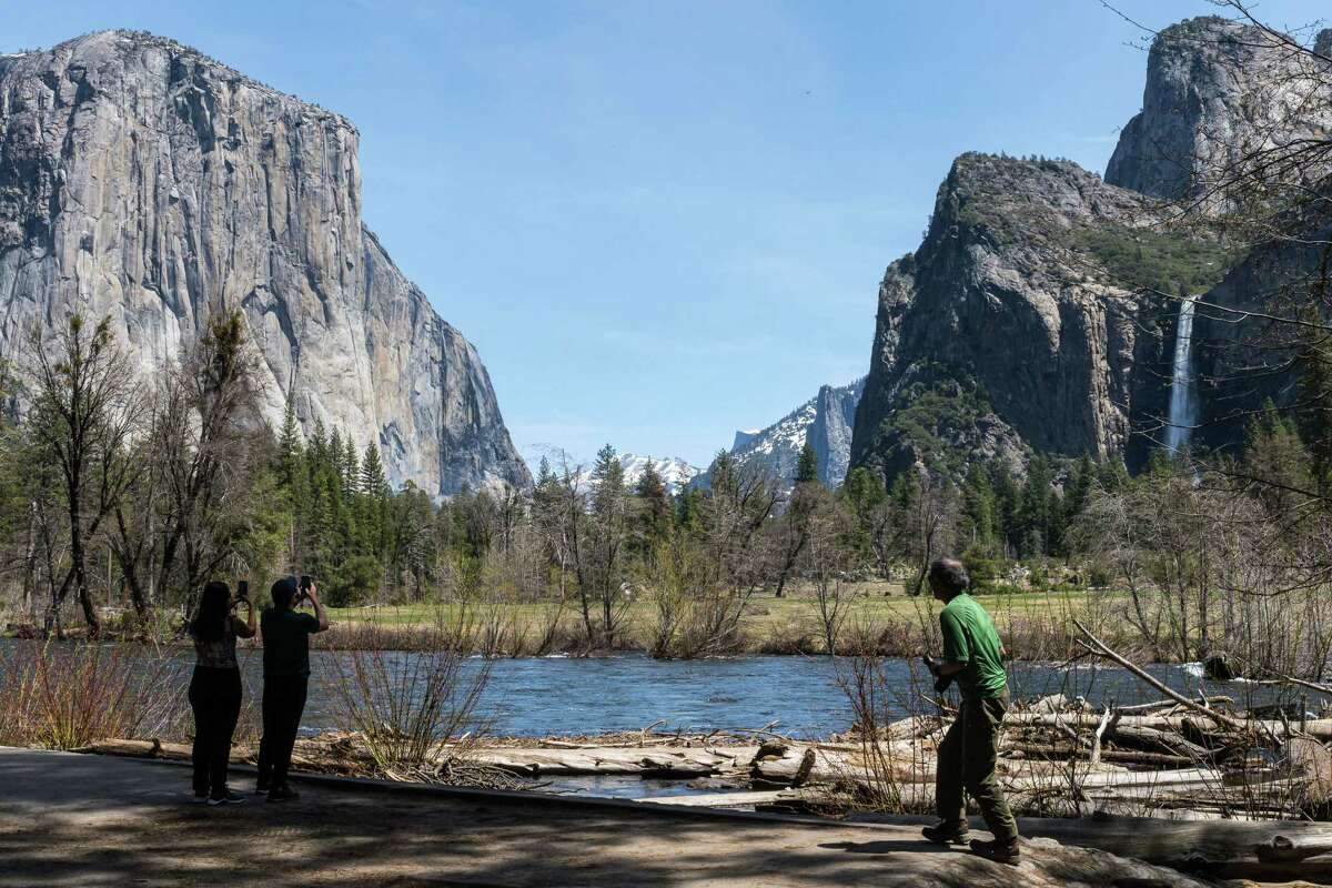 Yosemite National Park visitors stop for photos at the Valley View turnout, where the Merced River rises almost to the parking area.