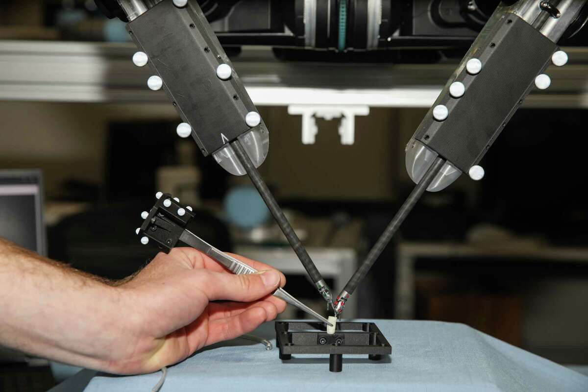 Николас Марион моделирует операцию с использованием медицинского робота Taurus SRI в кампусе SRI.  Робот оснащен инструментами DaVinci с датчиками, что обеспечивает точность во время операции.