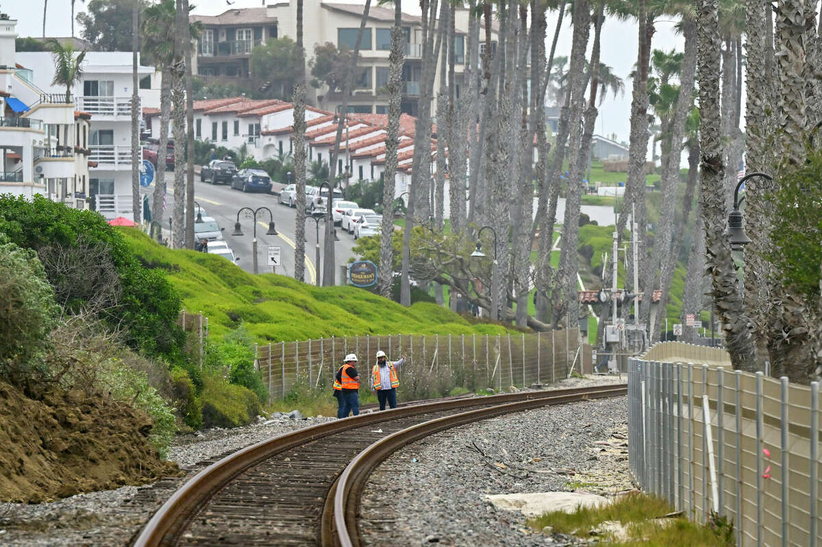 Rail workers check out the tracks below Casa Romantica in San Clemente on Friday, April 28, 2023. A landslide halted rail service in the area and caused four condos to be red-tagged out of concern for safety. 