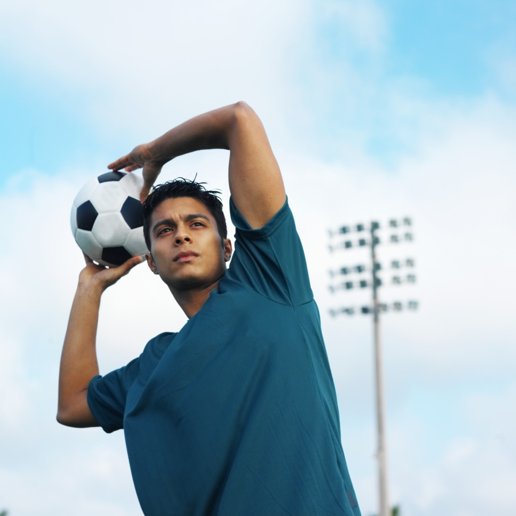 serious elderly doctor holds a soccer ball in one hand and points