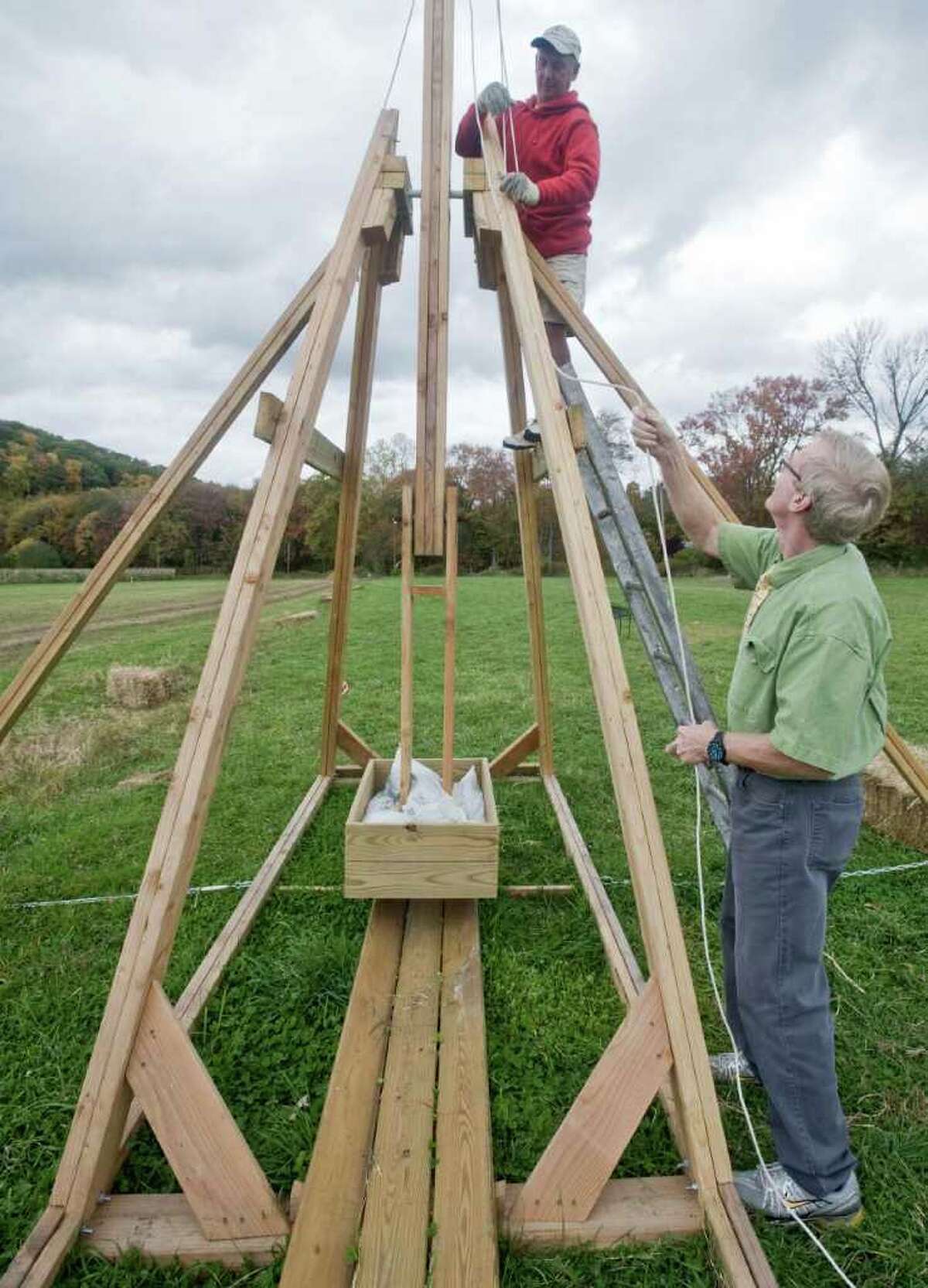 Newtown's Castle Hill Farm owner Steve Paproski works from the ladder as Newtown Middle School teacher Don Ramsey takes up the slack on the harness of a trebuchet, a medieval hurling machine that will launch pumpkins at the farm. Photo taken Thursday, Oct. 14, 2010
