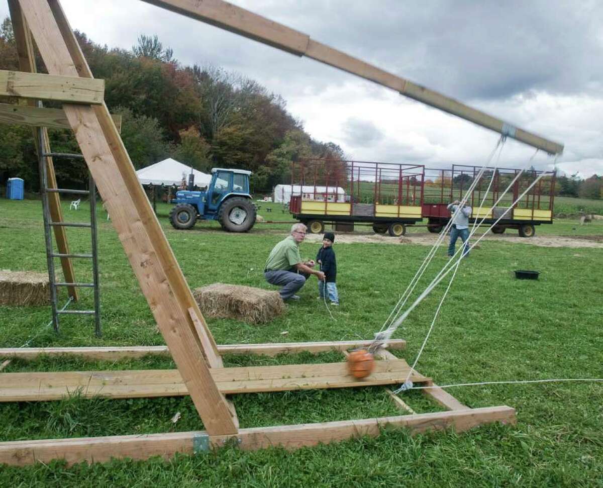Newtown Middle School teacher Don Ramsey and 4-year-old Jason Ford, of Santa Monica, Calif., launch a pumpkin from a trebuchet, a medieval hurling machine, at Castle Hill Farm in Newtown. Photo taken Thursday, Oct. 14, 2010