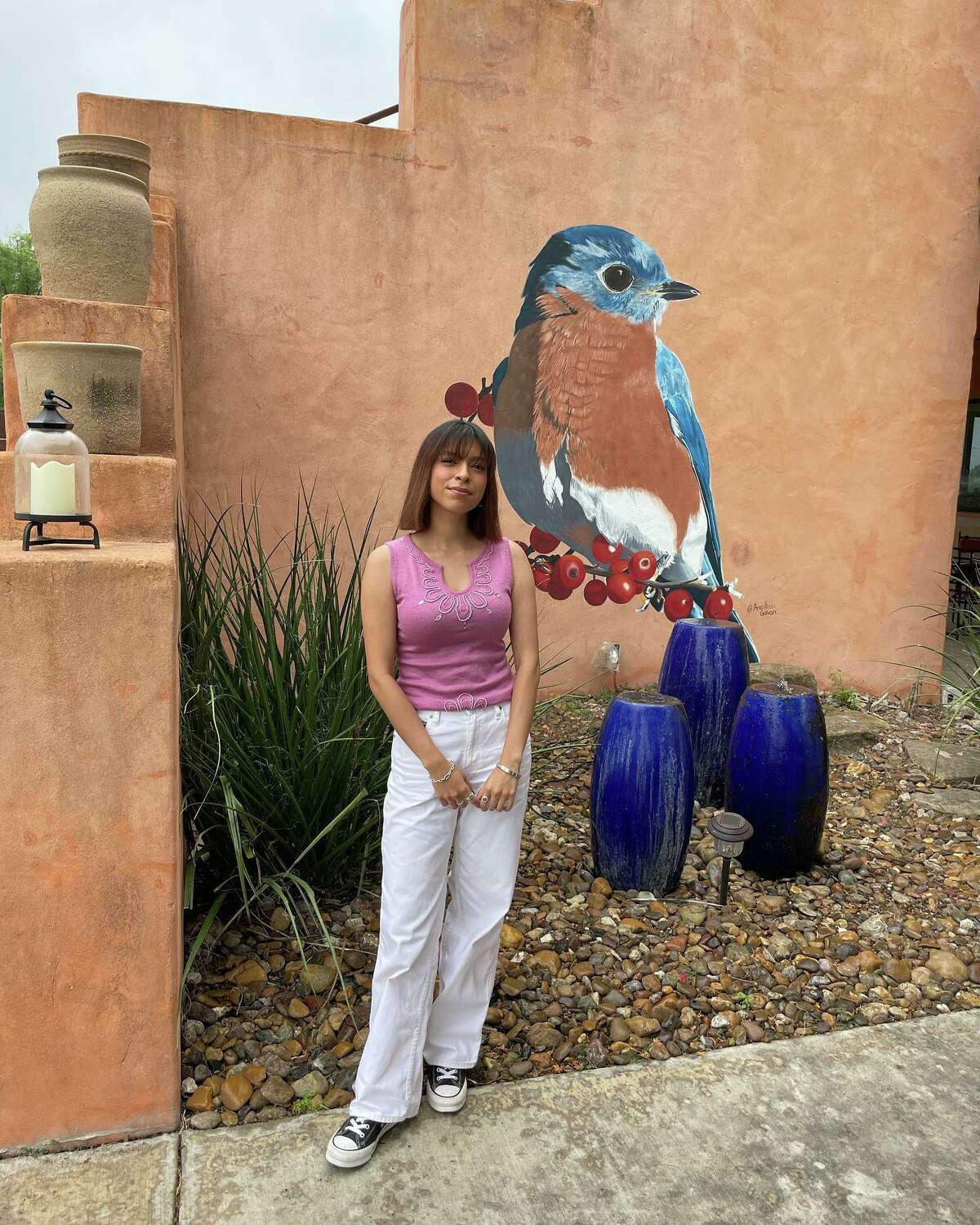 Laredo artist Anastasia Galvan is pictured with the city's newest public mural located at the Max A Mandel golf course. The mural features the male Eastern Bluebird and is based on her winning entry in the "Birds of the Brush" art contest.
