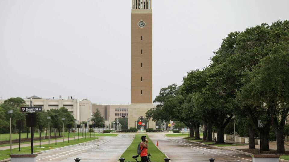 A person walks along Houston Street as the Albritton Bell Tower is seen in the background on Tuesday, July 7, 2020, at Texas A&M University in College Station.