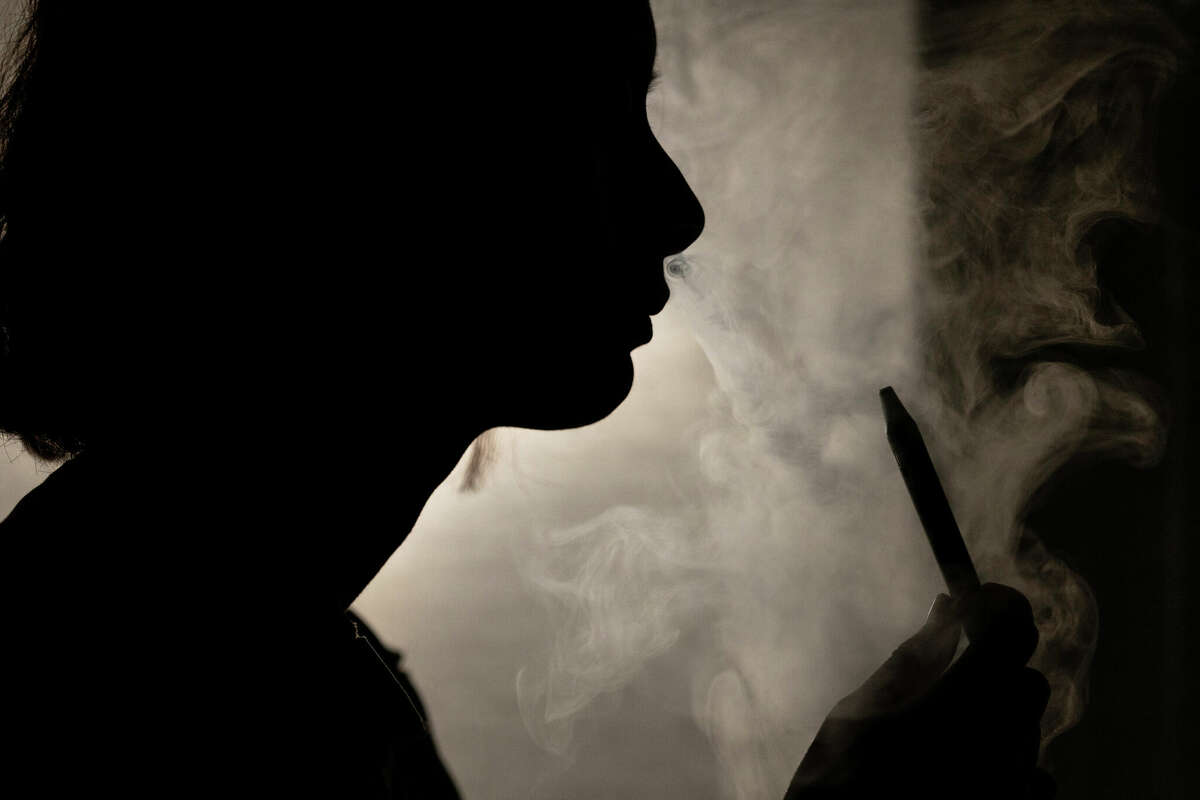 A person poses for a photograph as they vape in Melbourne, March 23, 2023. Recreational vaping will be banned as the government seeks to prevent the next generation from becoming addicted to nicotine, Australia's Health Minister Mark Butler said Tuesday, May 2, 2023.