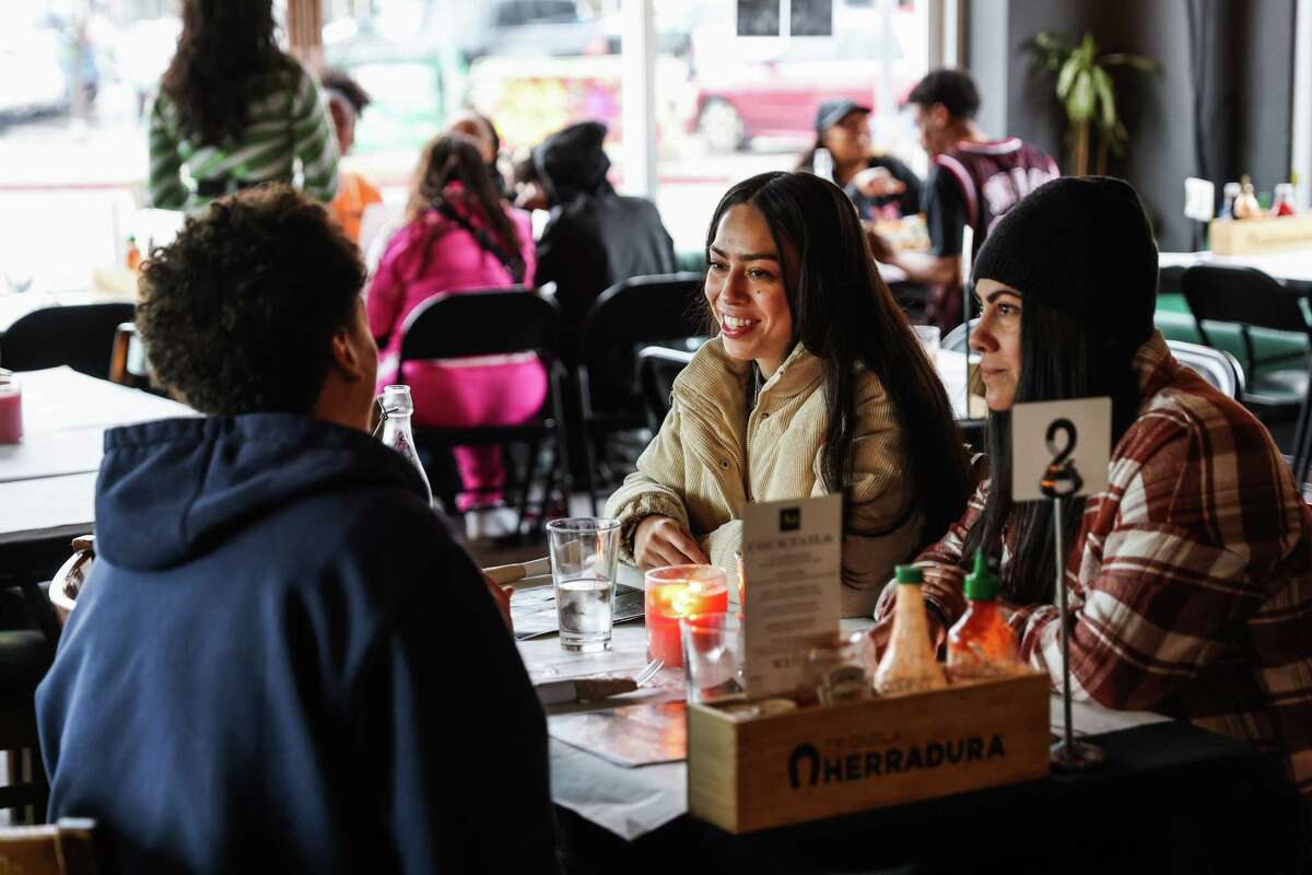 Melany Ramos (center) and Cristina Galvan (right) dine with a friend at Chef Smelly’s current pop-up location in Oakland.