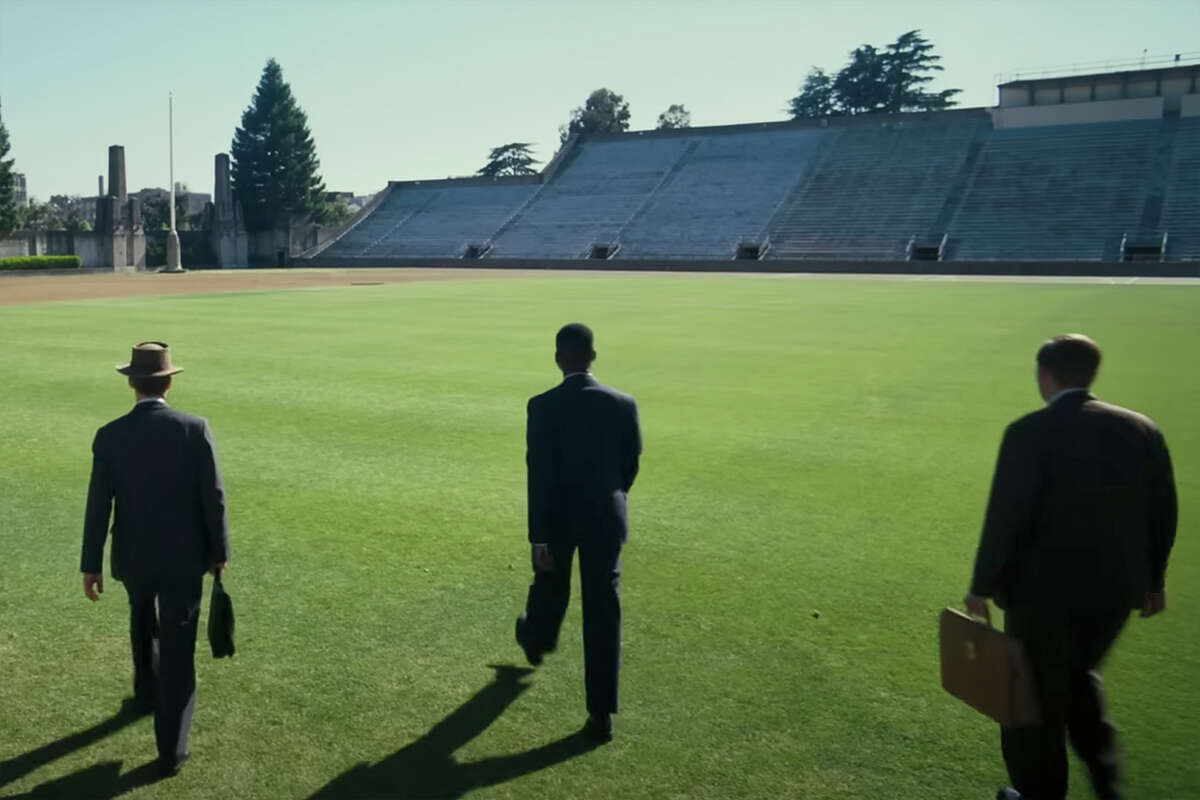 Three suits walk across the field at UC Berkeley's Edwards Stadium in the "Oppenheimer" trailer. 