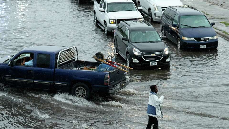 A good samaritan is directing vehicles to get around high water at North Freeway and East Tidwell Road Tuesday, May 9, 2023, in Houston.