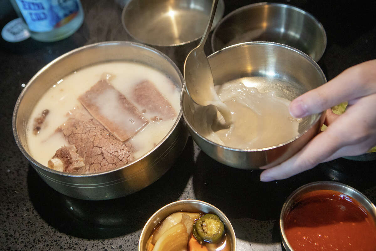 Tim Cheung of Bay Area Foodies pours some broth of Suyuk, boiled beef slices in a milky-white ox bone soup at Daeho Korean BBQ & Beef Soup on May 9, 2023. He is a social media influencer with hundreds of thousands of followers on Instagram and TikTok.