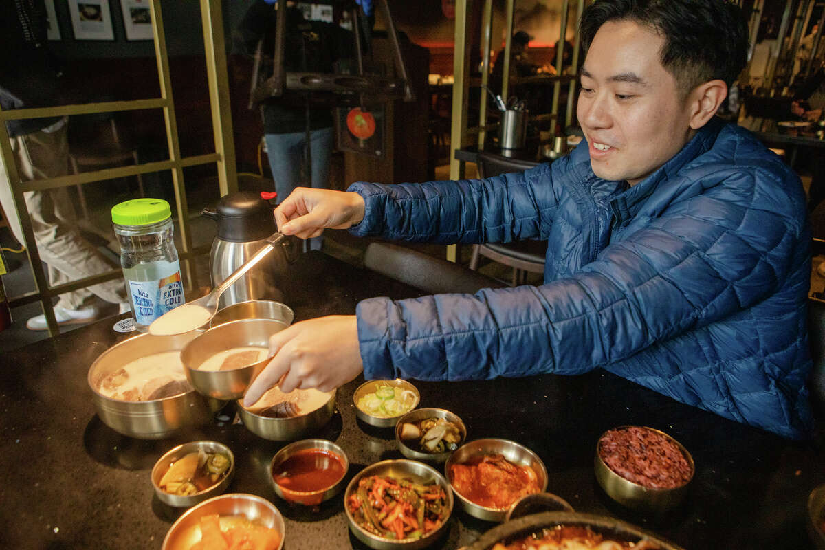 Tim Cheung of Bay Area Foodies pours some broth of Suyuk, boiled beef slices in a milky-white ox bone soup at Daeho Korean BBQ & Beef Soup on May 9, 2023. He is a social media influencer with hundreds of thousands of followers on Instagram and TikTok.