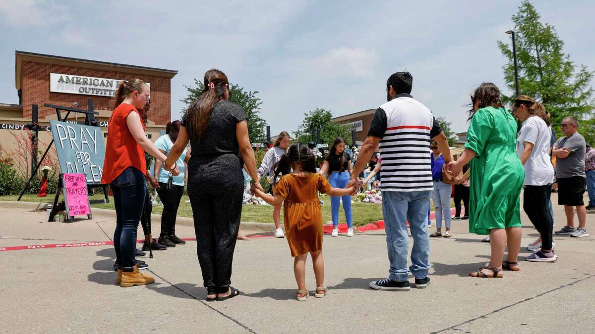 People hold hands as they pray at a memorial for victims of the Allen Premium Outlets mass shooting, Tuesday, May 9, 2023, in Allen, Texas. (Elías Valverde II/The Dallas Morning News via AP)