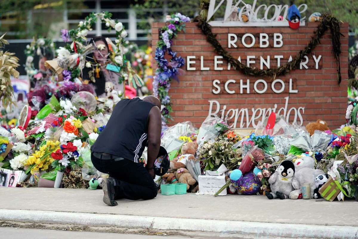 FILE - Reggie Daniels pays his respects at a memorial at Robb Elementary School, June 9, 2022, in Uvalde, Texas. The memorial was created to honor the victims killed in the mass shooting at the school. The litany of Texas’ mass killings in just the last few years is staggering — one of which occurred in Uvalde when more than 20 people were killed in 2022. Guns have long been a part of Texas culture, but to equate the number of guns with the number of people killed by guns strikes some as a false equivalence.