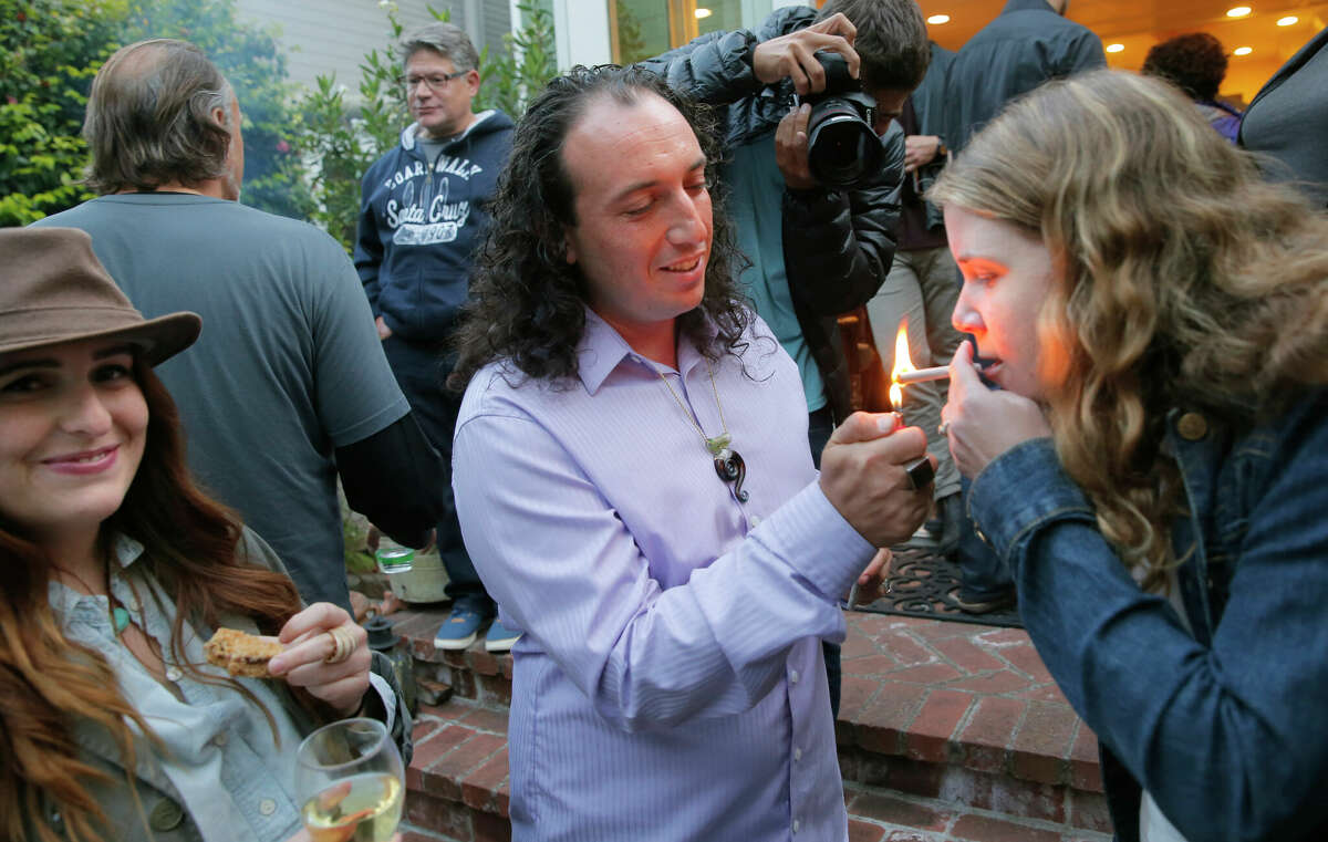 Nicholas Kashmir lights up a joint for Ellen Holland, both of Oakland, at a food and weed tasting event at the Coal Valley House in San Francisco, California, as seen Thursday.  June 11, 2015 