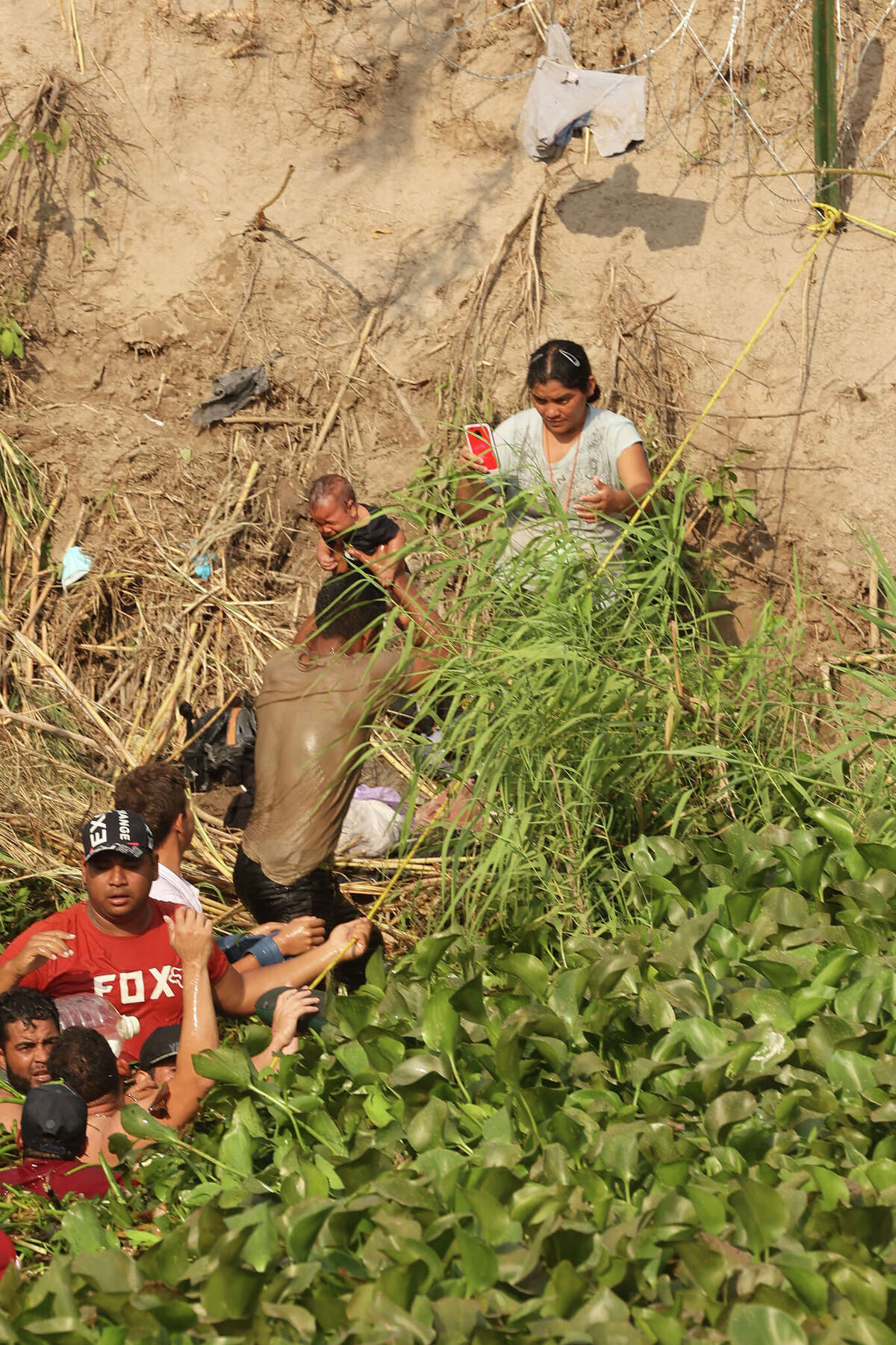 Migrants crossing the border carry a baby across Rio Grande, barely