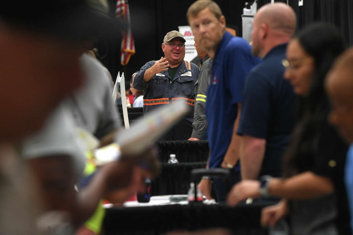 Cody Smith with Kinder Morgan talks with co-workers as they work their booth at the Spring Job Fair hosted by Workforce Solutions at the Bob A. Bowers Civic Center in Port Arthur. Photo made Thursday, May 11, 2023 Kim Brent/Beaumont Enterprise