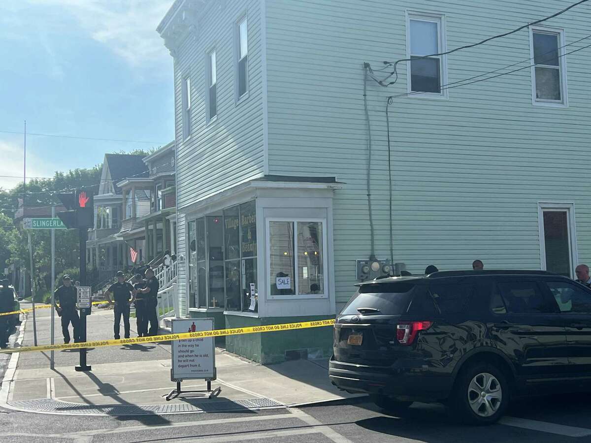 Albany police officers stand outside the Village Barber and Beauty shop at 221 Second Ave. where two men and a boy were wounded in a shooting on Saturday, May 13, 2023 in Albany.