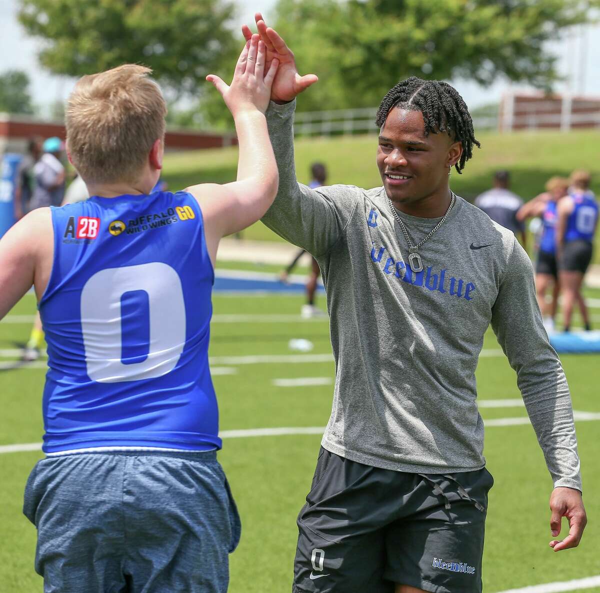 Chandler Rivers gives a high-five to a local player at a youth football camp Saturday at Beaumont ISD Stadium.