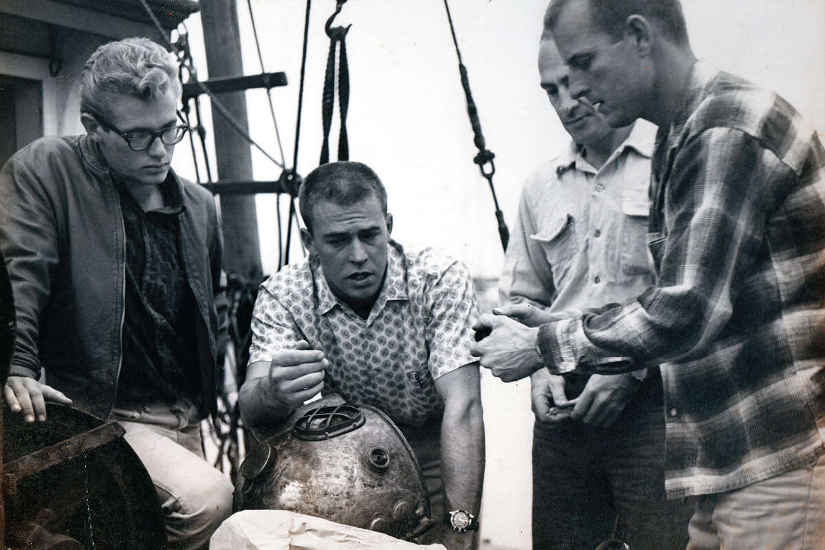 Left to right, an unidentified man, Jim Houtz, Warren Whitney and Dan Wilson view the the bonnet of the modified Japanese helmet that Wilson would use for his historic 400-foot dive. 