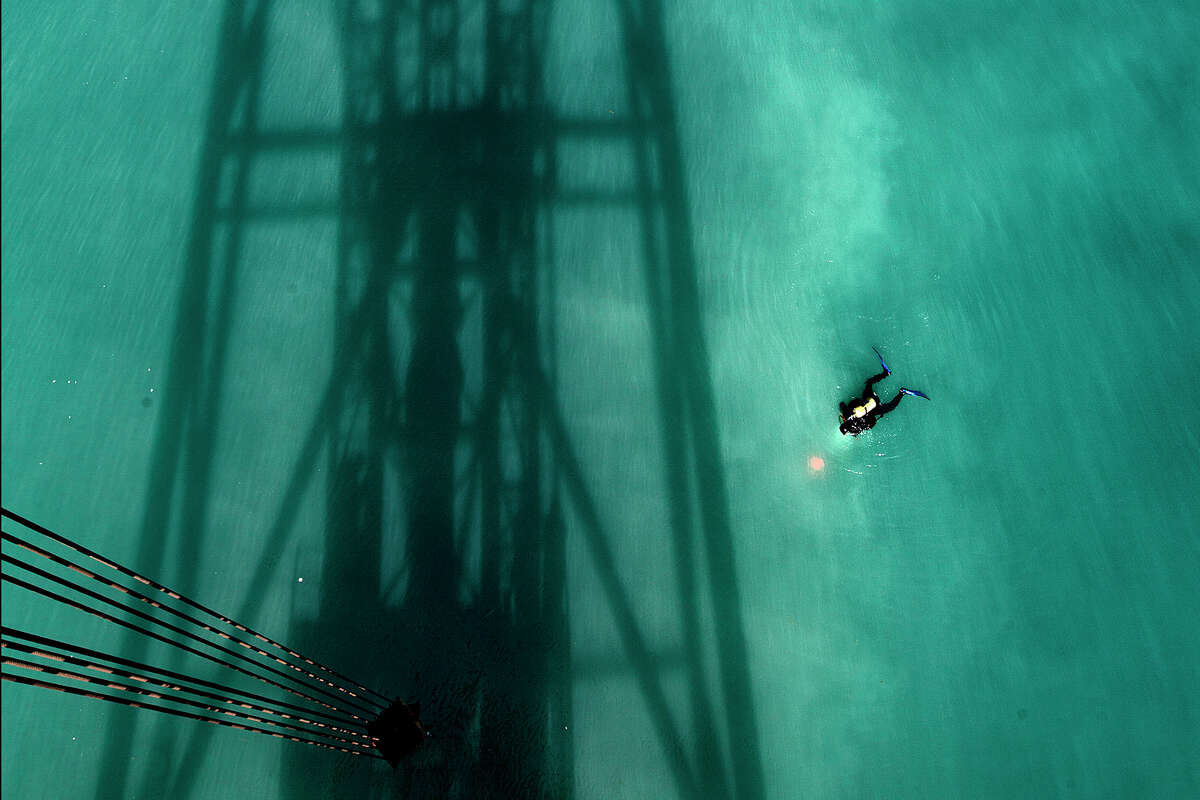 A commercial diver prepares to submerge in the shadow of an oil platform. 