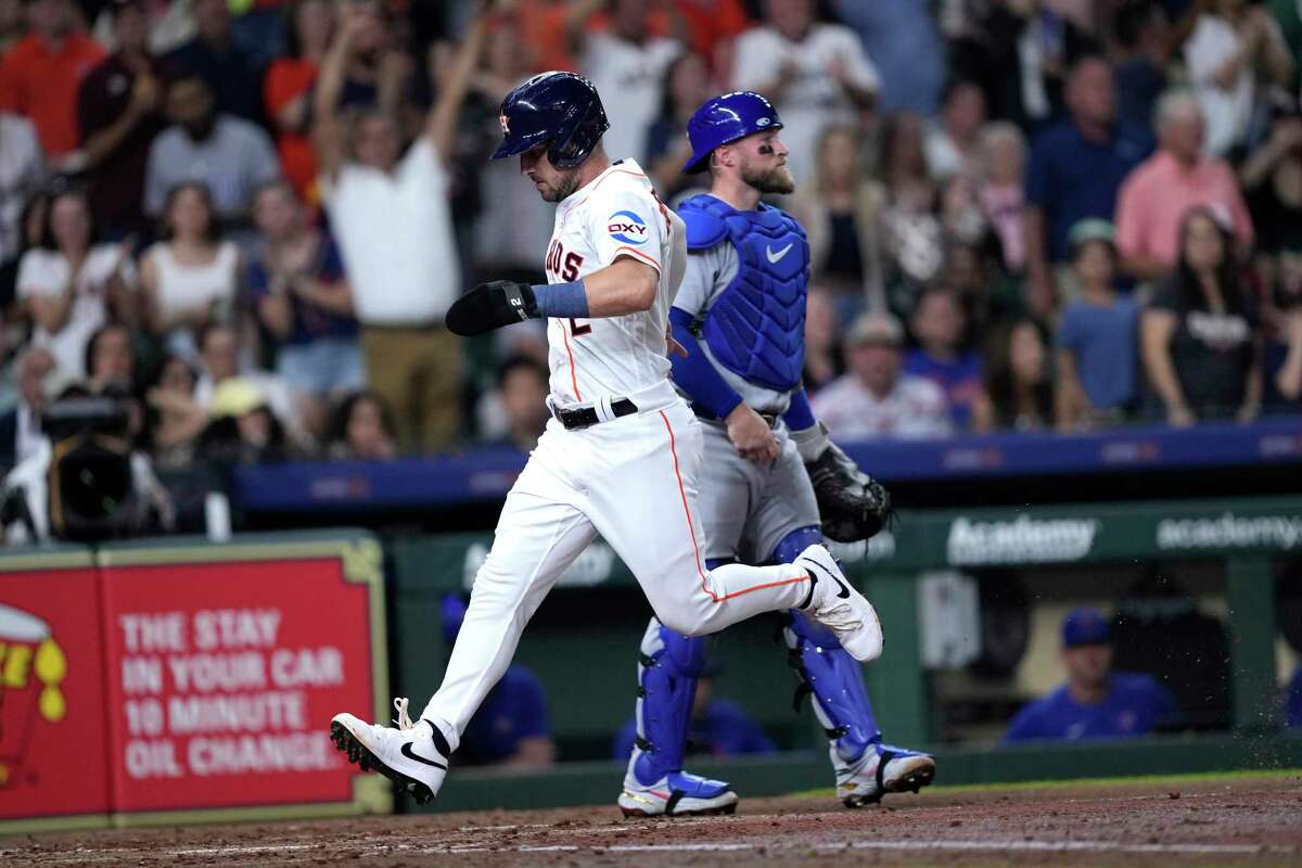 Houston Astros' Alex Bregman (2) scores as Chicago Cubs catcher Tucker Barnhart stands behind home plate during the fourth inning of a baseball game Tuesday, May 16, 2023, in Houston.
