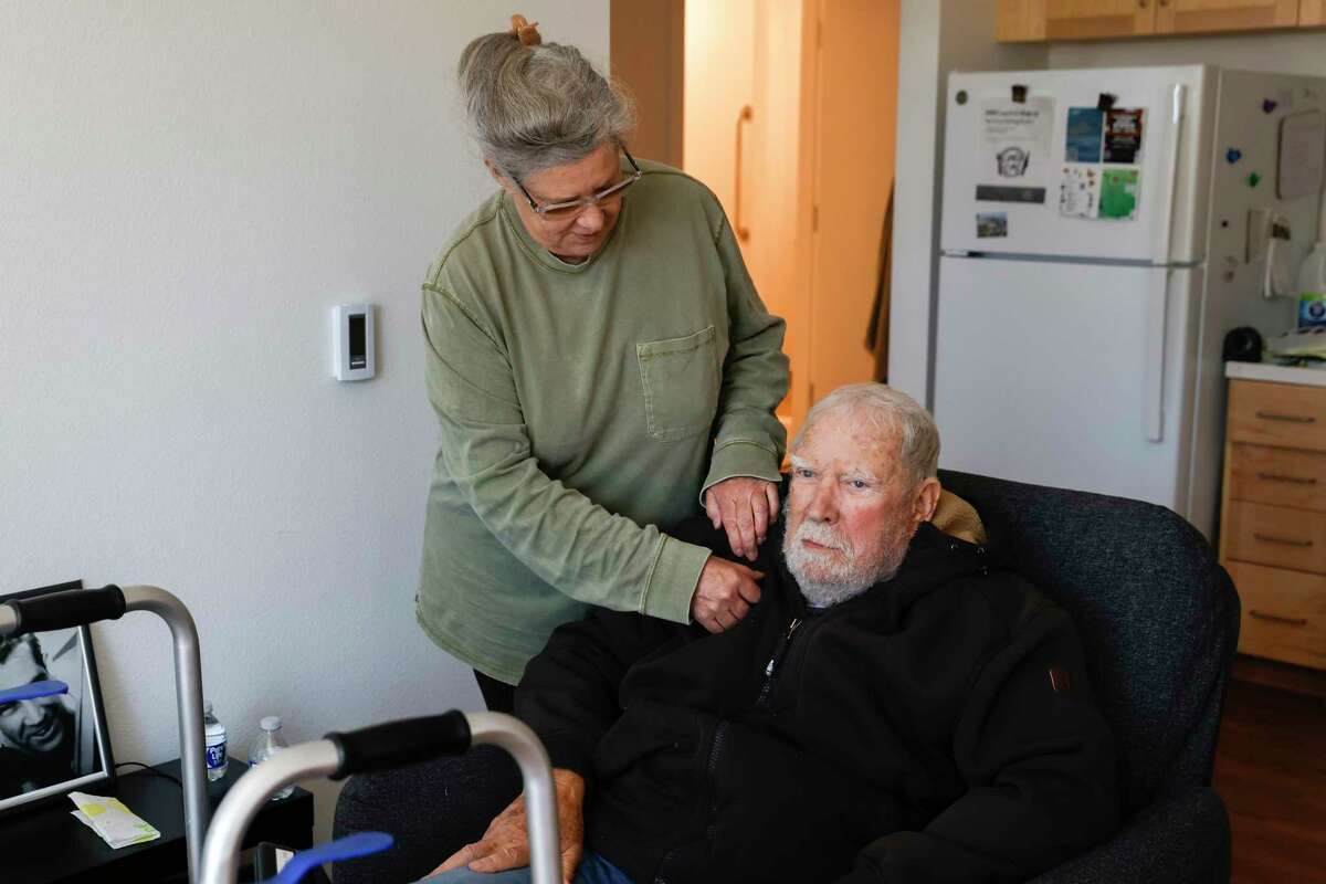 Air Force veteran Regina Record, 62, helps her father, Grant Record, 86, adjust his collar as they share their apartment in the newly constructed Maceo May veterans' living complex on Treasure Island in San Francisco on Tuesday, May 16, 2023 is.