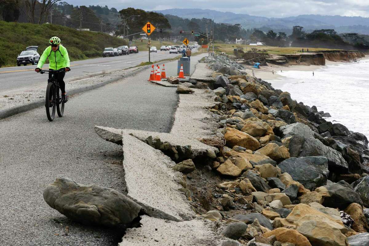 A cyclist rides past a crumbling sidewalk and eroding rocks along the shores of Surfer’s Beach in Half Moon Bay, Calif. Friday, May 5, 2023. 25% to 70% of California?s beaches may erode completely by 2100, according to new research from US Geological Survey.
