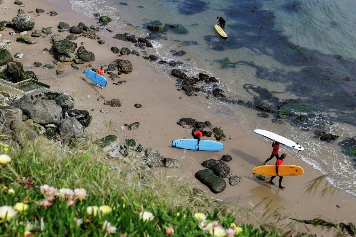 Surfers prepare to head out from Cowell Beach. A new report projects that up to 70% of California beaches could disappear by the end of the century if more isn’t done to curb greenhouse emissions and take measures to protect the coast.