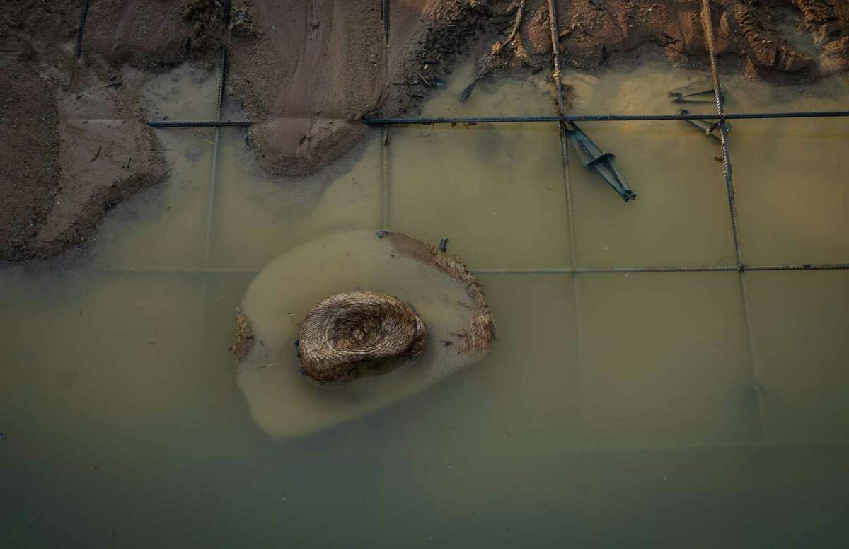 A straw hat sits in a puddle at the scene where a house under construction collapsed in high winds Tuesday, May 23, 2023, in Conroe. Officials said that two people were killed and seven were injured.