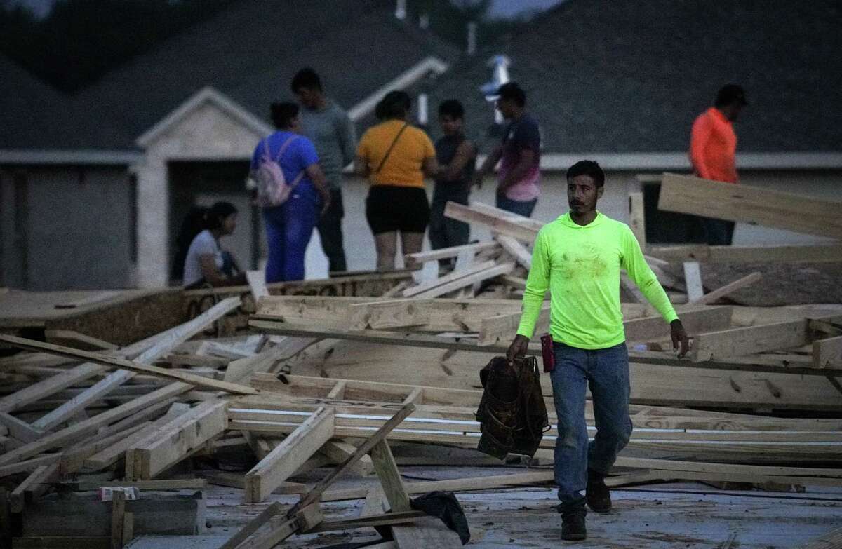 Josue Benitez gathers tools at the site where a house under construction collapsed in high winds Tuesday, May 23, 2023, in Conroe. Officials said two people were killed and seven were injured. Benitez said he was working at the scene.