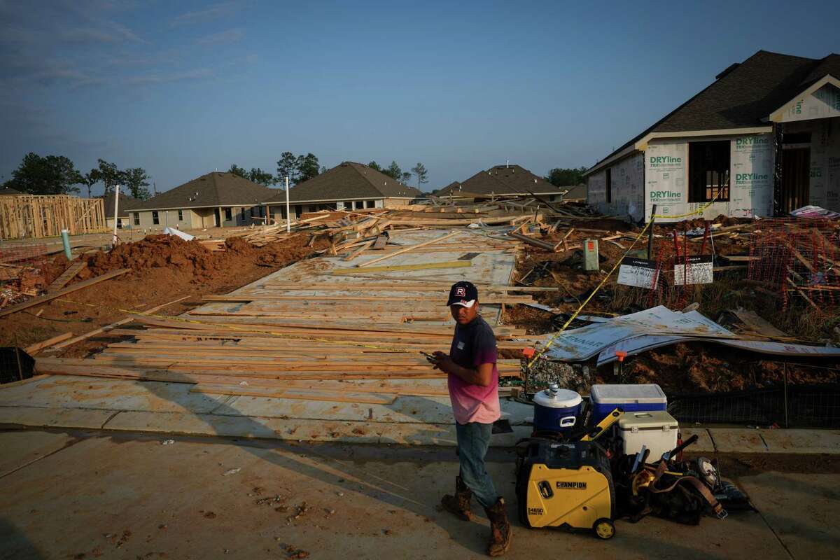 A man gathers tools at the scene where a house under construction collapsed in high winds Tuesday, May 23, 2023, in Conroe. Officials said two people were killed and seven were injured.