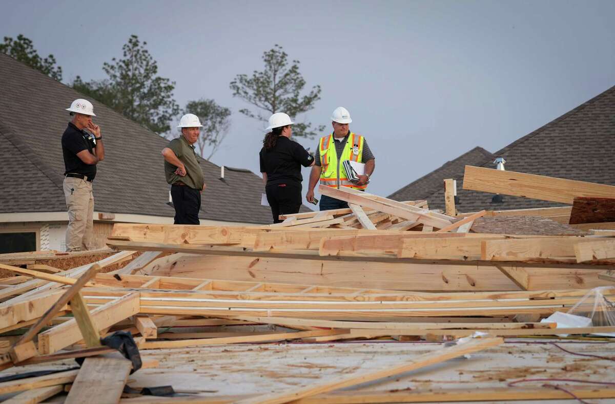 Officials from Lennar homebuilders talk with a compliance officer from the Occupational Safety and Health Administration, at right, at the site where a home under construction collapsed in high winds Tuesday, May 23, 2023, in Conroe. Officials said two people were killed and seven were injured.