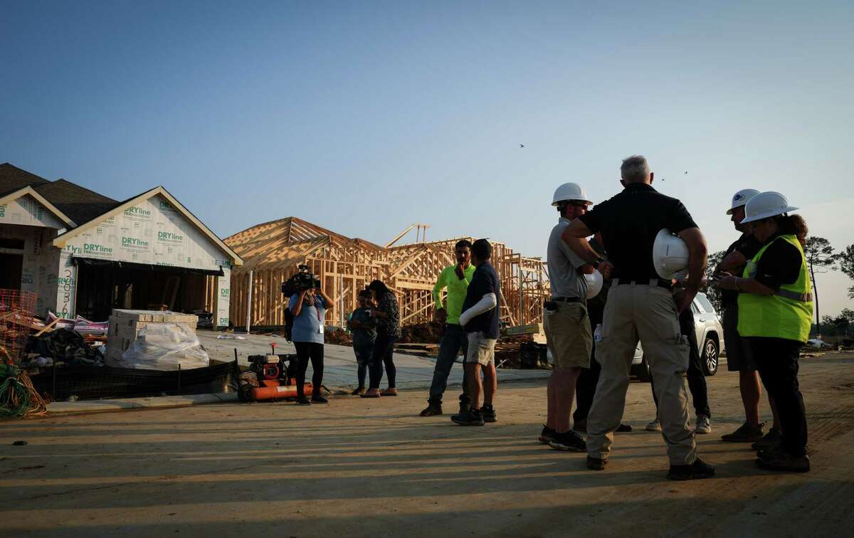 Officials from Lennar Homes, workers and journalists gather at a scene where a house under construction collapsed in high winds Tuesday, May 23, 2023, in Conroe. Officials said that two people were killed and seven were injured.