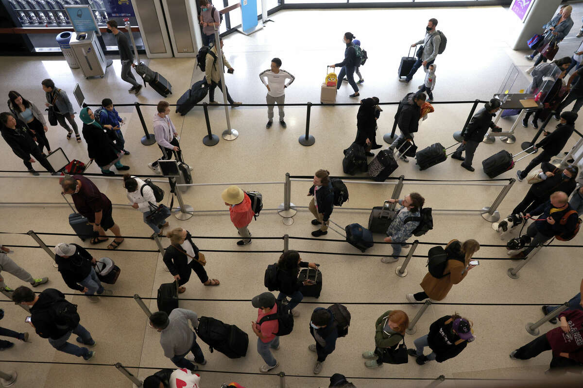 FILE: Travelers line up to enter a security checkpoint at SFO on July 1, 2022, in San Francisco. The airport is bracing for passenger numbers that near 2019 levels this Memorial Day weekend.