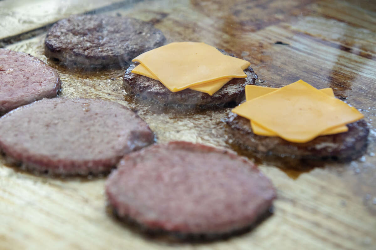 burger patties, some topped with American Cheese, are cooked on a flat top grill at Bud's Giant Burgers in Vallejo, Calif. on May 24, 2023.