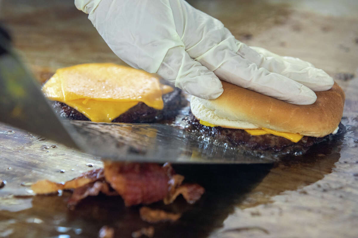 Alma Gutierrez finishes cooking a cheeseburger on the flat top grill at Bud's Giant Burgers in Vallejo, Calif. on May 24, 2023.