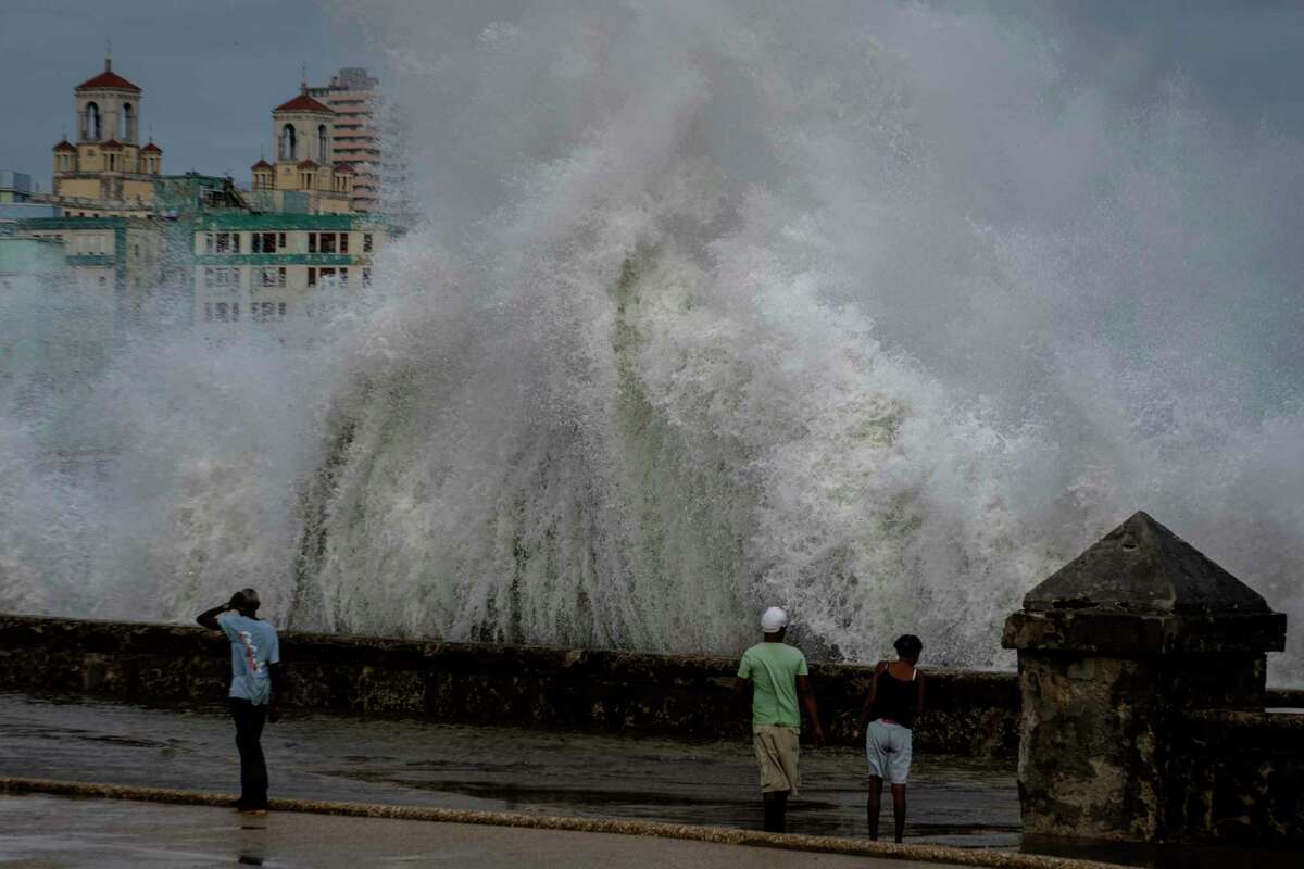 FILE - People stand along a waterfront as huge waves crash against a seawall in the wake of Hurricane Ian in Havana, Cuba, Wednesday, Sept. 28, 2022. National Oceanic and Atmospheric Administration on Thursday, May 25, 2023, announced its forecast for the 2023 hurricane season.