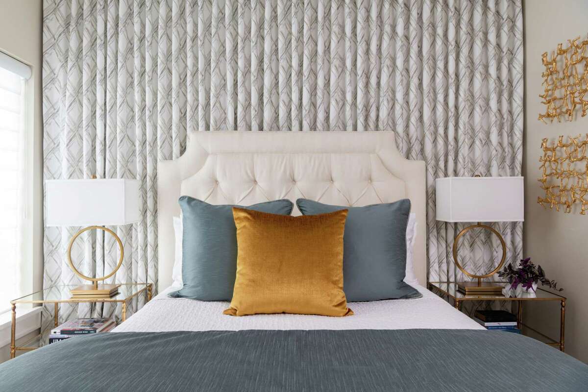 In this guest bedroom, a wall of draperies brings color and pattern to the room, but it also camouflages a small, awkwardly-placed window.