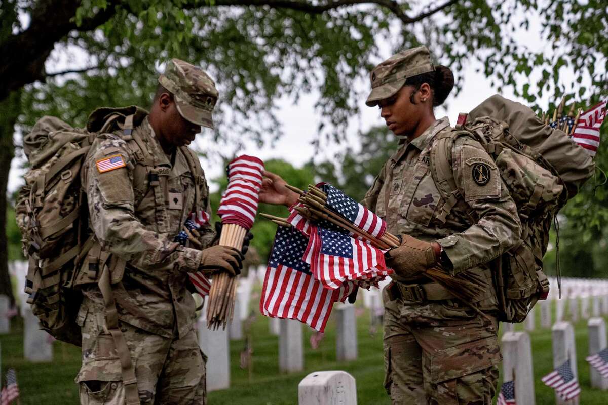 Members of the 3rd U.S. Infantry Regiment also known as The Old Guard, place flags in front of each headstone for "Flags-In" at sunrise at Arlington National Cemetery in Arlington, Thursday, May 25, 2023, to honor the Nation's fallen military heroes ahead of Memorial Day.