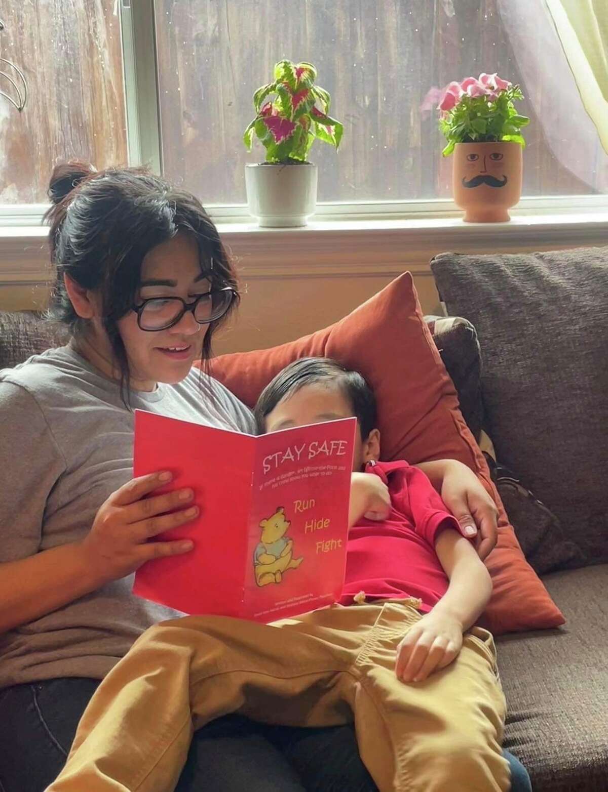 Cindy Campos reads the book "Stay Safe" to her son in Dallas. Cindy Campos' 5-year-old son was so excited about the book that had been sent home with him from school featuring Winnie-the-Pooh that he wanted to read it immediately. But her heart sank as she flipped through the pages advising children what to do if “danger is near,” including locking doors, turning off the lights and quietly hiding till police arrive. (Cindy Campos via AP)