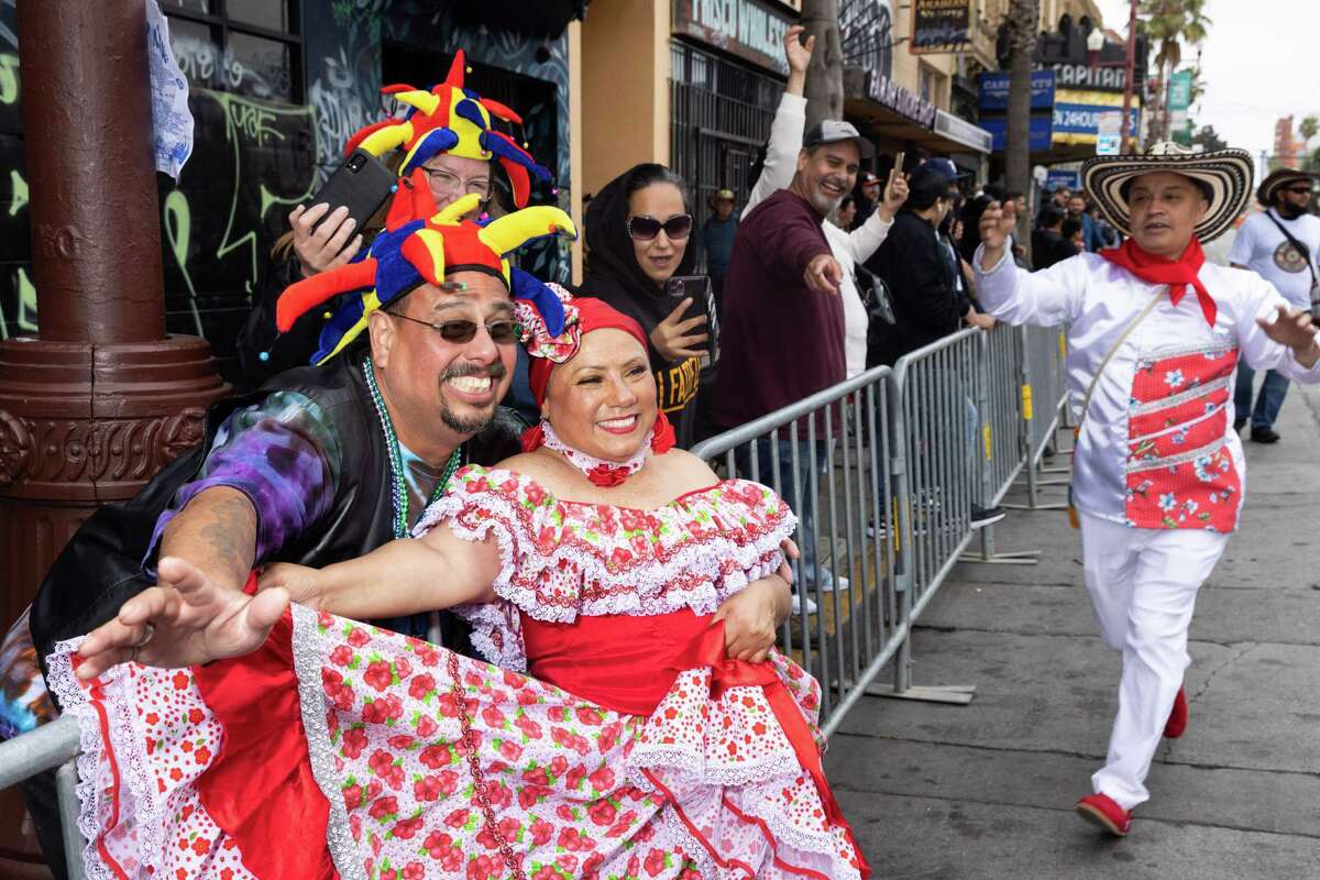 El espectador Joseluis Sandoval (izquierda) posa para una fotografía con un participante en el Gran Desfile de Carnaval en Mission Street en San Francisco el domingo.