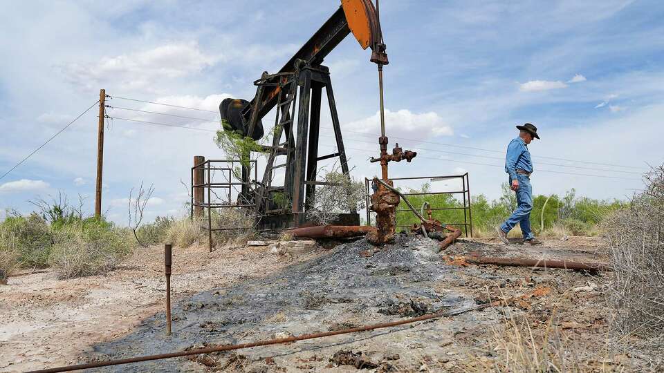 Schuyler Wight walks away from a well as it leaks oil and produced water onto the surface of his ranch on Wednesday, April 26, 2023 in West Texas.