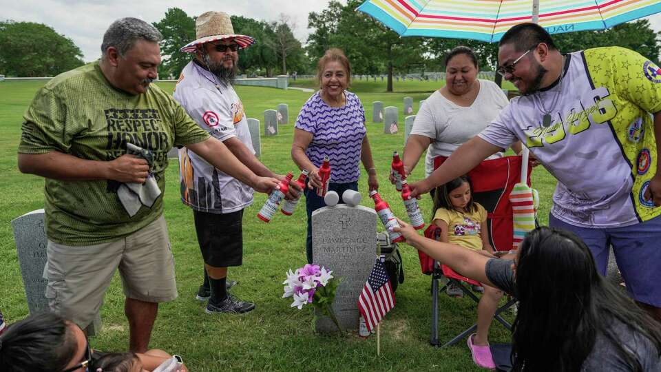 Five generations of the Martinez family gather and cheers at the grave of Army Veteran, Lawrence Martinez after a Veterans Day Memorial Service on Monday, May 29, 2023 at Houston National Cemetery in Houston.