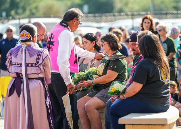 A woman gets a smudged eagle feather waved over her shoulder as Woolsey Walking Sky during the cedar ceremony during the fifth year anniversary remembrance ceremony and dedication of the Warrior Spirit sculpture at Santa Fe High School on Thursday, May 18, 2023 in Santa Fe.