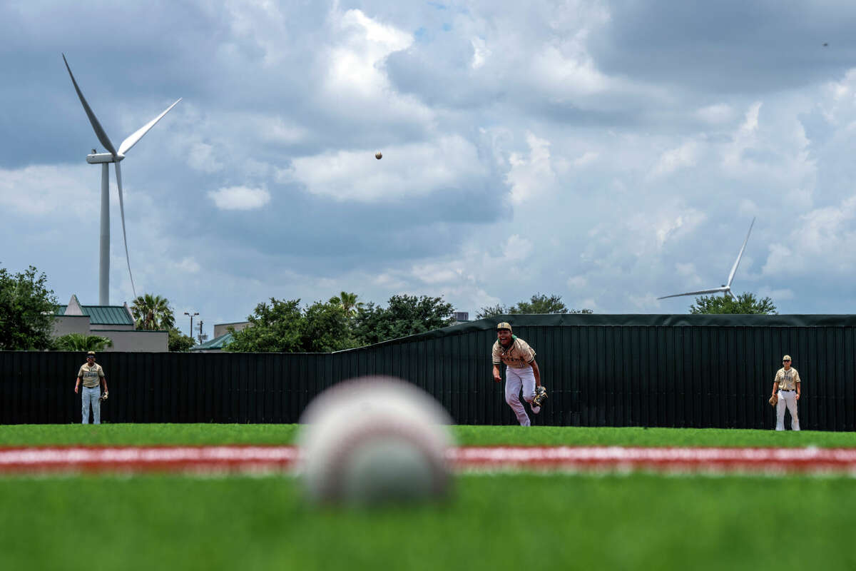 Members of the Lyford high school baseball team practice on a new athletic field partially funded by wind turbine tax bonds in Lyford, a city in the Rio Grande Valley. Industrial energy-producing wind turbines cover hundreds of acres of farmland in the area.