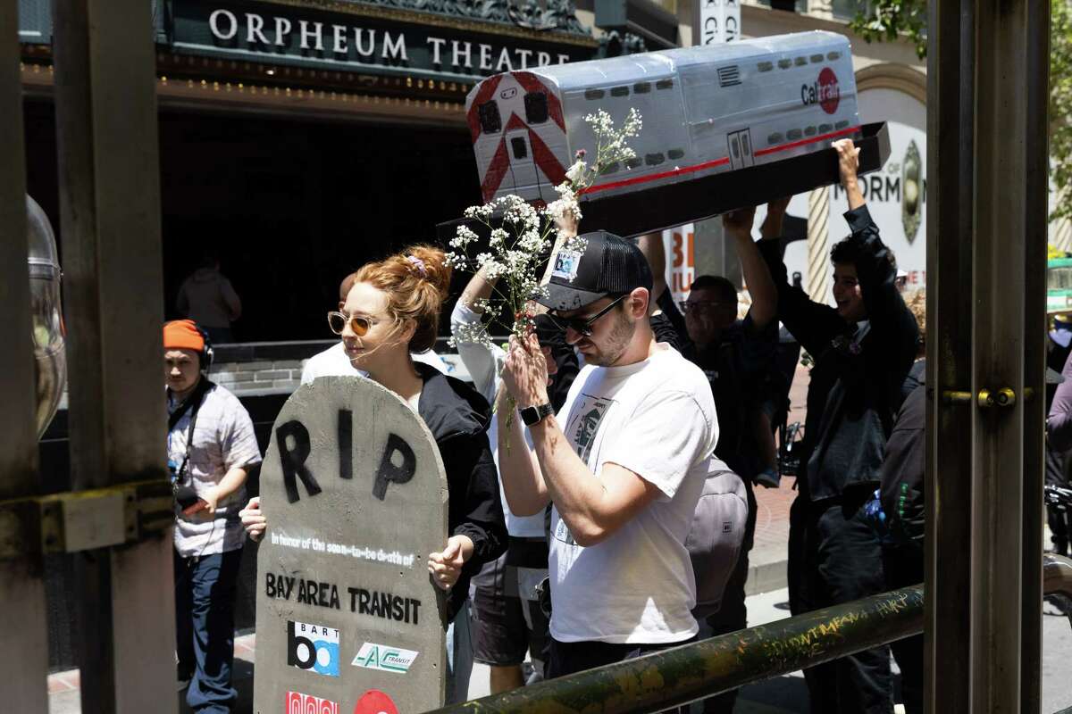 A group carries a model Caltrain car during a mock funeral procession in San Francisco, a rally for public transit funding.  Proponents called for more funding to be allocated to the state's public transit companies.