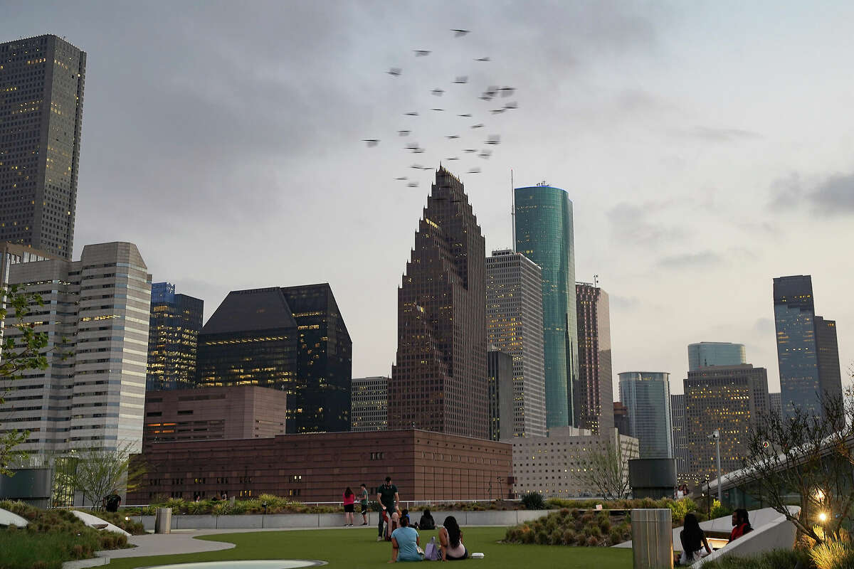 Birds fly by as people watch the Houston skyline as the sunsets on Monday, March 6, 2023 in Houston.