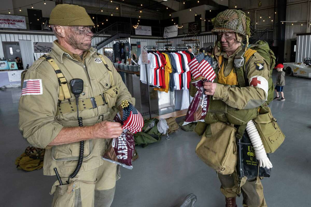 Drew Hodges hands Michaela Serseloudi, of Latham, American flags and Hershey’s bars prior to jumping out of a C-47 airplane that flew on D-Day in 1944. The Airborne Demonstration Team were wearing authentic gear identical to paratroopers on D-Day during an exhibition at the third annual Wings & Wheels showcase to benefit the Prescott Foundation, which restores and maintains WWII aircraft and vehicles, at the Hangar at 743, on Saturday in Colonie.